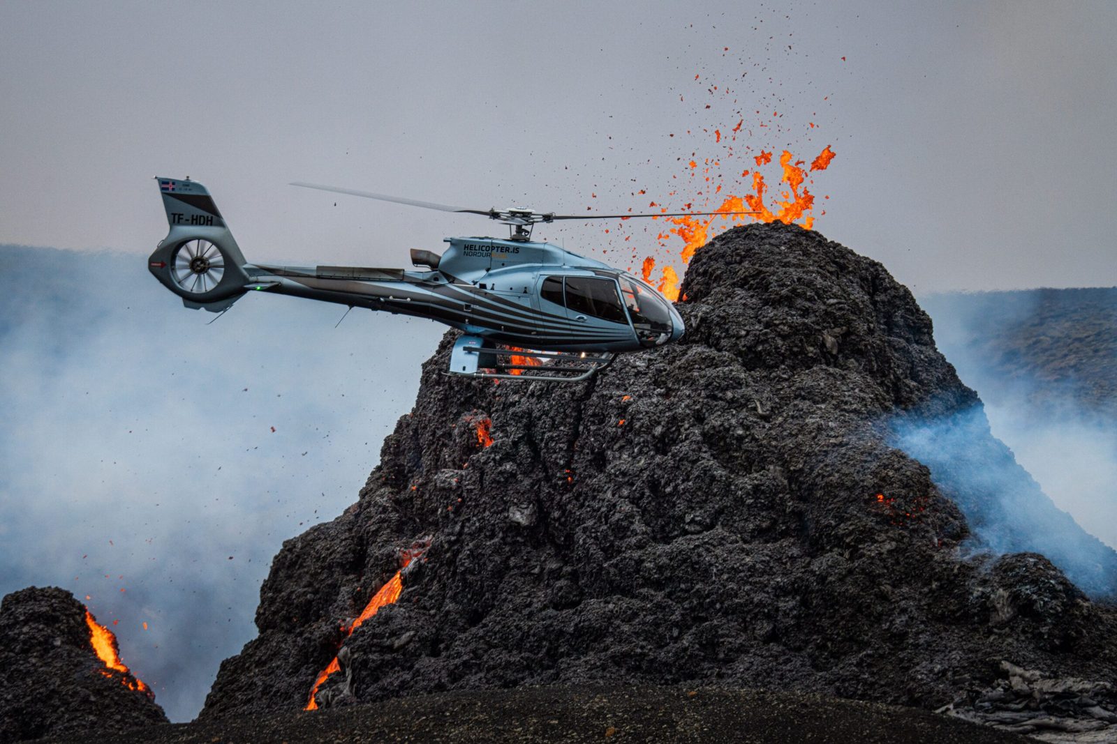 A helicopter beside an erupting crater